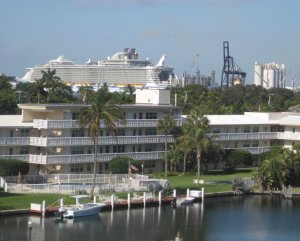 Cruise ship docked at Port Everglades, one mile from Lago Mar, with hotel and palm trees in background.